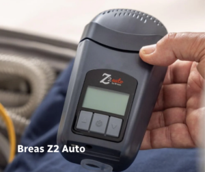 Breas Z2 Auto travel CPAP machine shown handheld, featuring a compact design for portable sleep apnea treatment.