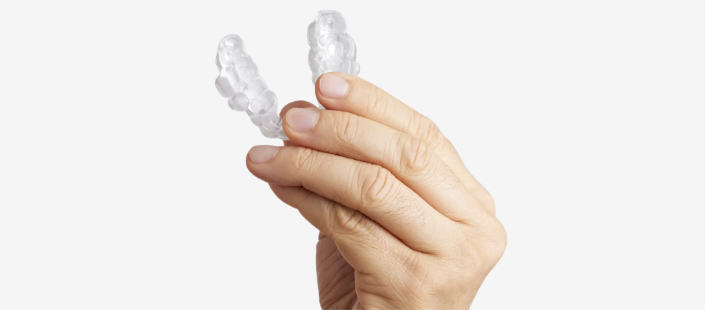 Custom mandibular advancement oral appliance for sleep apnea treatment, shown held in hand and designed to keep the airway open during sleep.